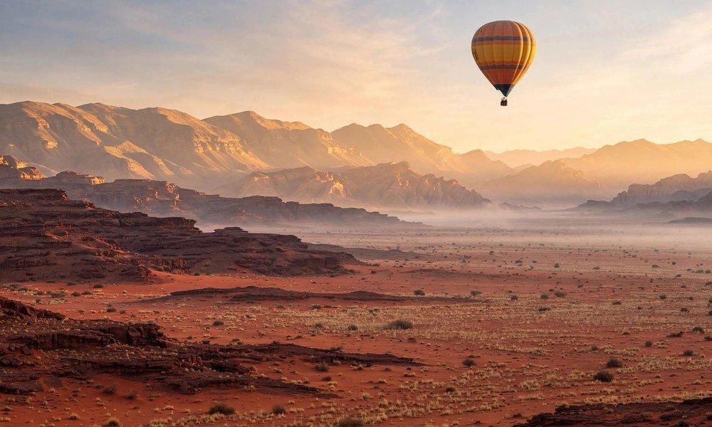 Hot air balloon drifting over red desert plains at sunrise near Alice Springs