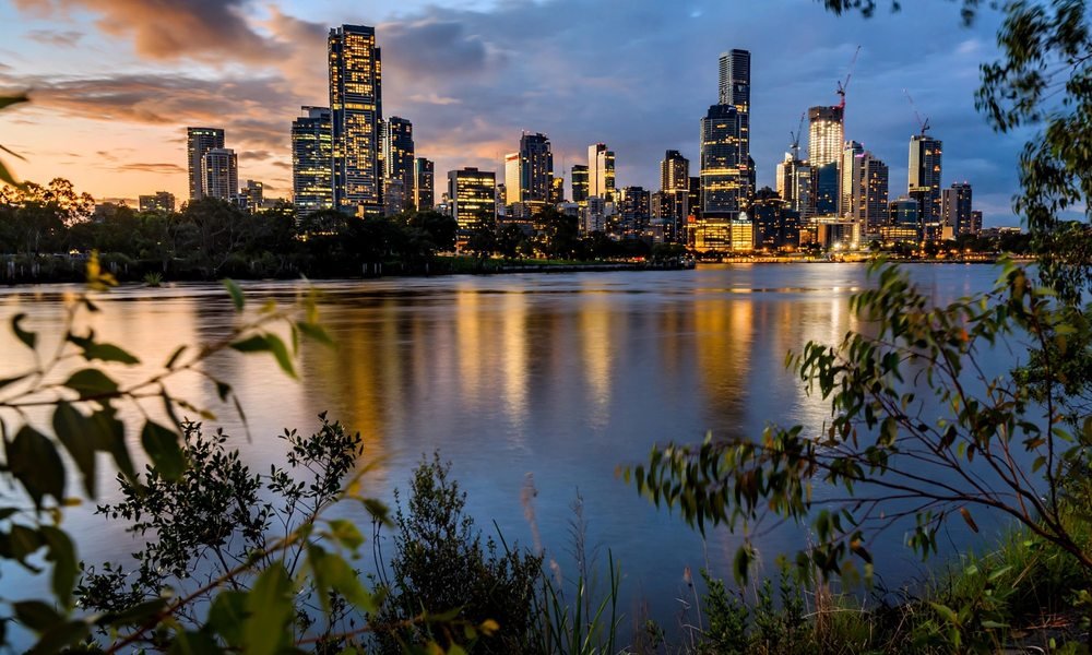 Brisbane city skyline across the Brisbane River at dusk, seen from a riverside hotel area