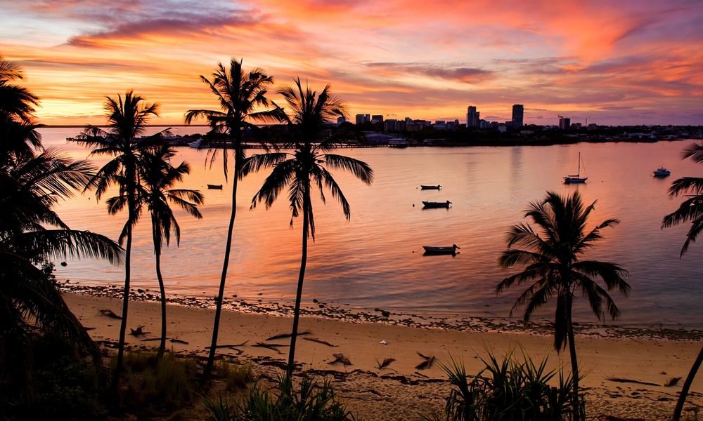 Sunset over Darwin Harbour in the Northern Territory with palm trees and boats