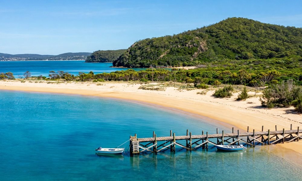 Shoal Bay beach in Port Stephens with white sand, calm turquoise water and headlands